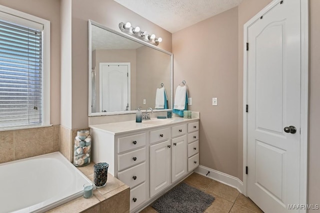 full bathroom featuring baseboards, a garden tub, tile patterned flooring, a textured ceiling, and vanity