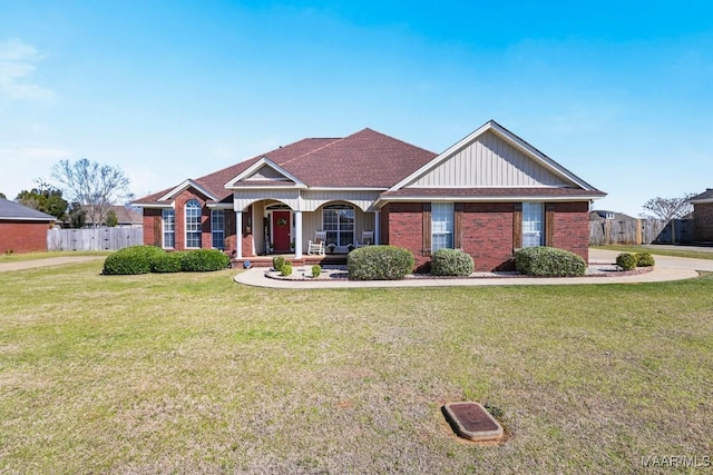 view of front facade with a porch, fence, a front lawn, and brick siding