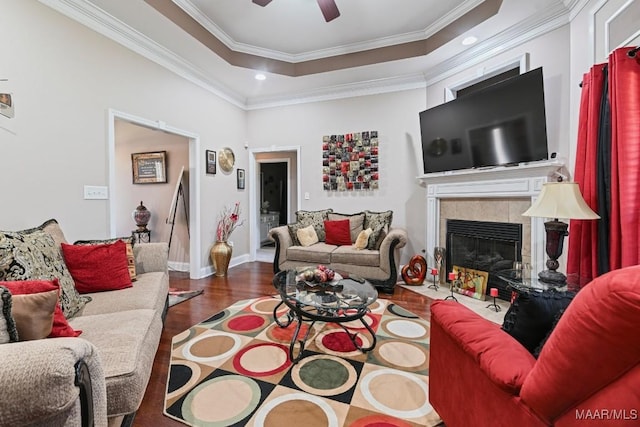 living room featuring a tile fireplace, wood finished floors, a ceiling fan, and crown molding