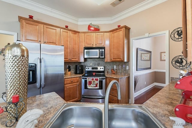 kitchen with visible vents, brown cabinetry, decorative backsplash, appliances with stainless steel finishes, and a sink