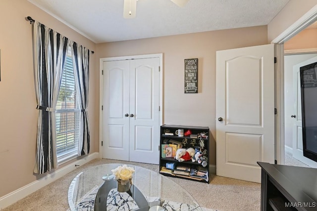 interior space featuring ceiling fan, carpet floors, a textured ceiling, and baseboards