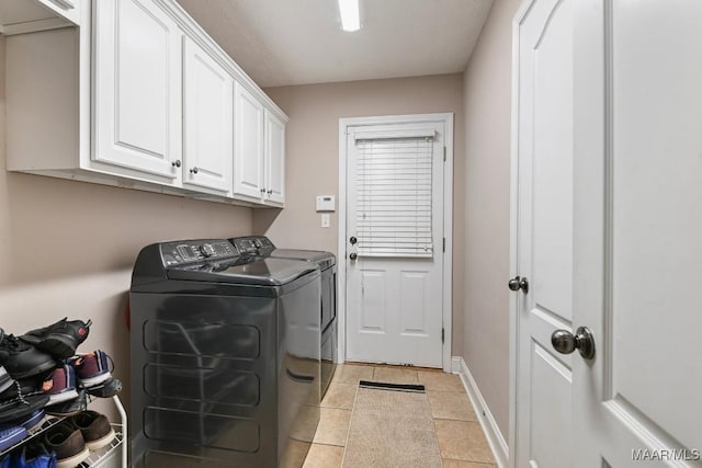 laundry area featuring light tile patterned flooring, cabinet space, baseboards, and separate washer and dryer