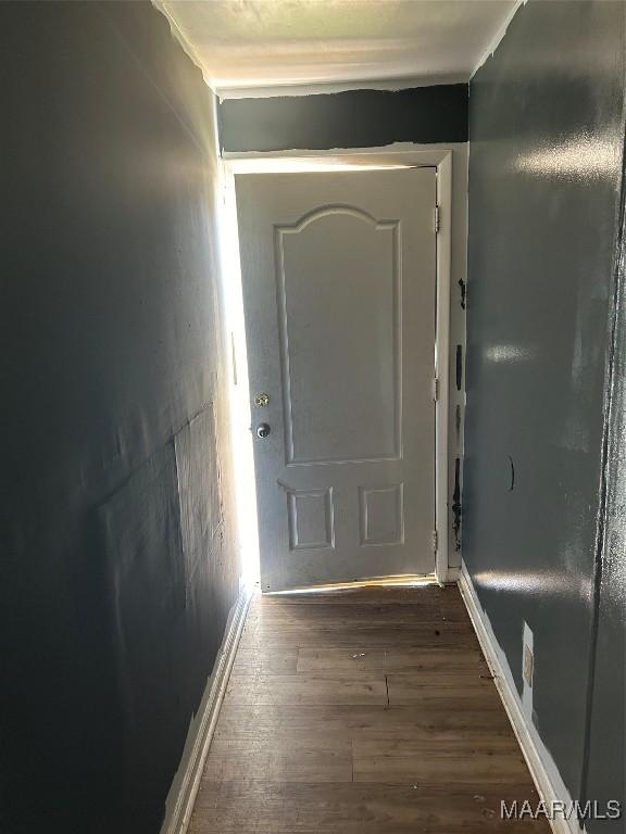 doorway to outside featuring baseboards and wood finished floors