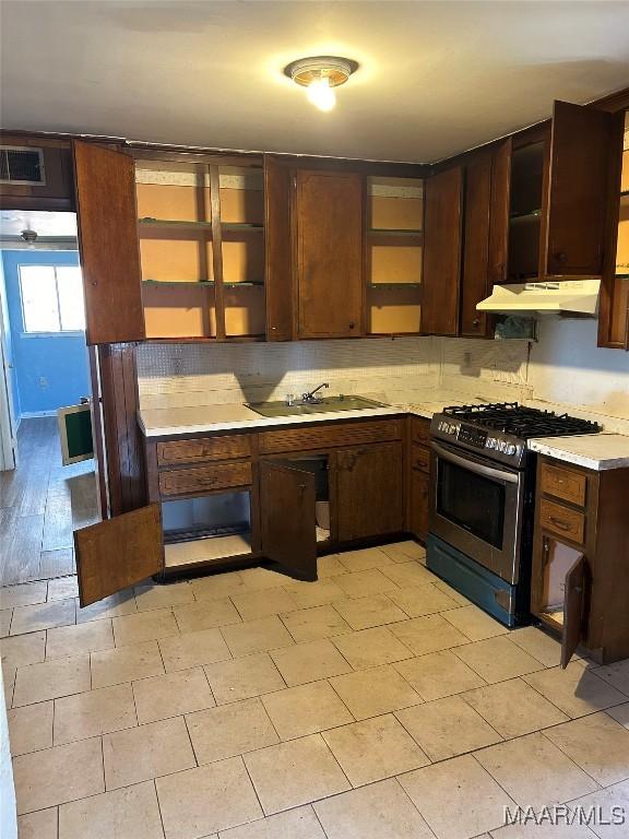 kitchen featuring light countertops, visible vents, decorative backsplash, stainless steel gas stove, and under cabinet range hood