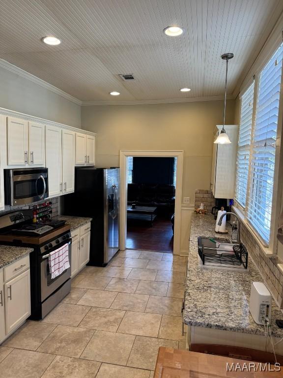 kitchen featuring white cabinets, light stone counters, hanging light fixtures, stainless steel appliances, and crown molding