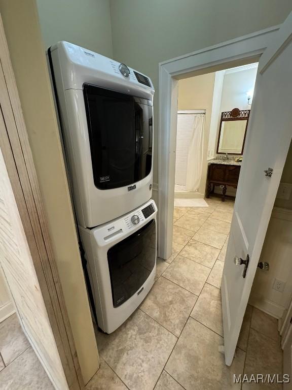 washroom with stacked washing maching and dryer, laundry area, and light tile patterned flooring