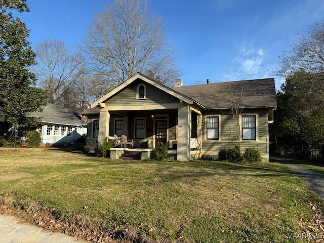 view of front of property featuring covered porch, a chimney, and a front lawn