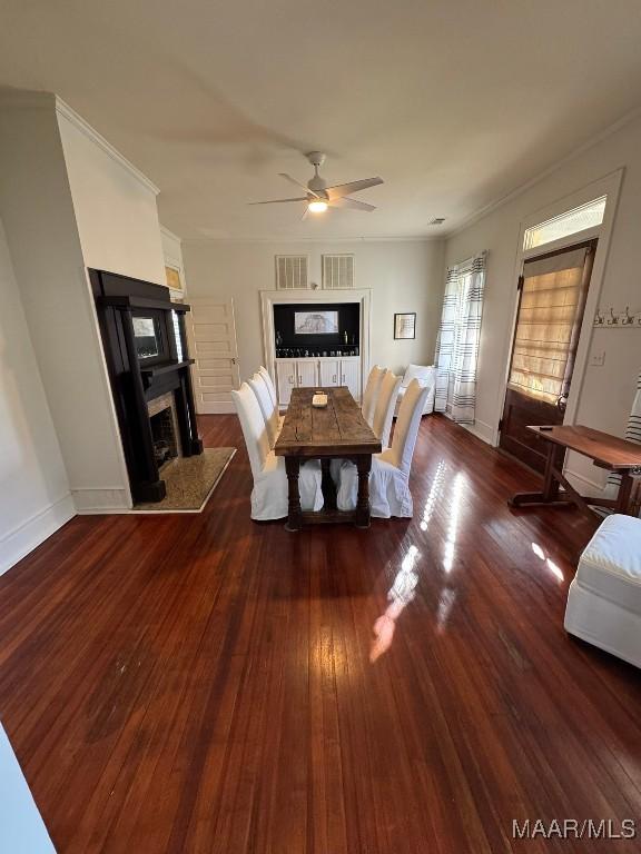 dining room with wood-type flooring, a fireplace, baseboards, and a ceiling fan