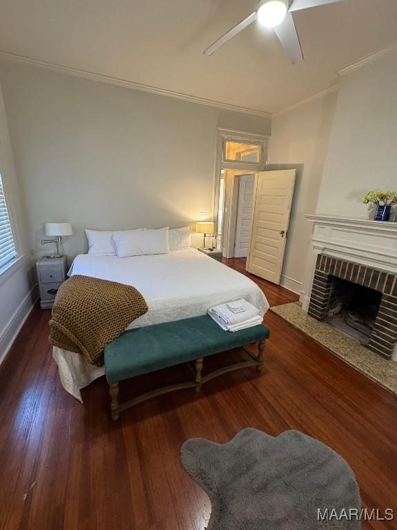 bedroom with ornamental molding, a brick fireplace, and hardwood / wood-style flooring