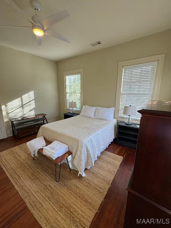 bedroom with dark wood-type flooring, visible vents, and ceiling fan