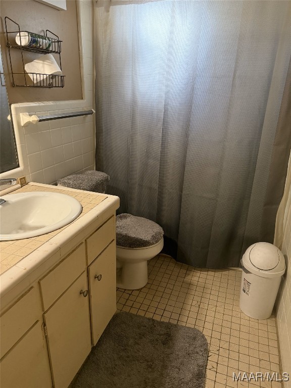 full bathroom featuring toilet, tile walls, vanity, and tile patterned floors