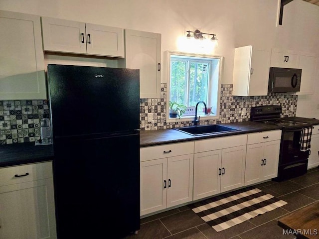 kitchen featuring dark countertops, backsplash, white cabinets, a sink, and black appliances