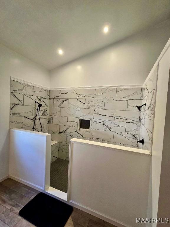 interior space featuring a walk in shower, vaulted ceiling, and wood finished floors