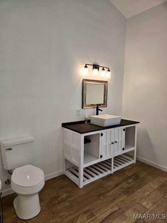 bathroom with vanity, wood finished floors, toilet, and baseboards