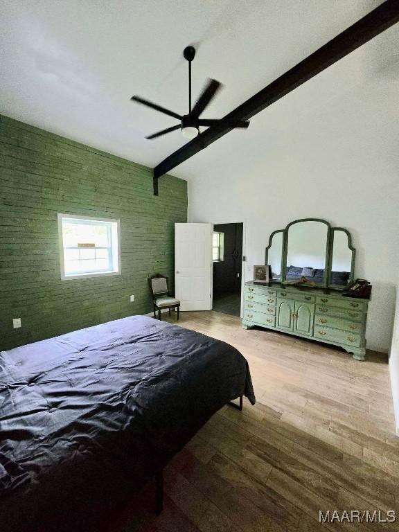 bedroom featuring brick wall, an accent wall, wood finished floors, high vaulted ceiling, and beam ceiling