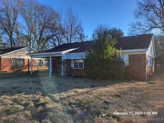 view of front of home with driveway, a carport, and brick siding