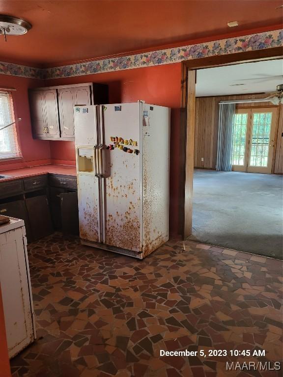 kitchen featuring stone finish flooring, white refrigerator with ice dispenser, ceiling fan, and dark colored carpet