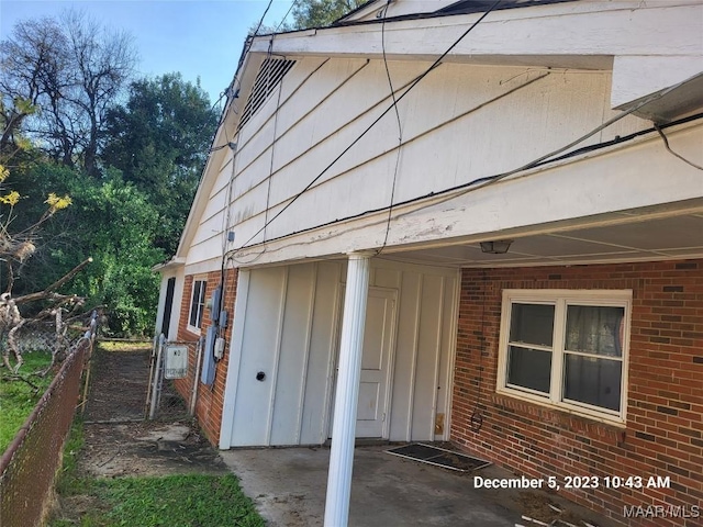 view of side of property featuring brick siding and fence