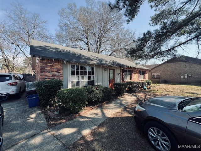 ranch-style home with roof with shingles and brick siding