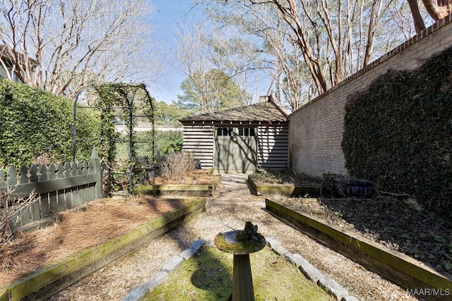 exterior space with a garden, fence, and an outbuilding