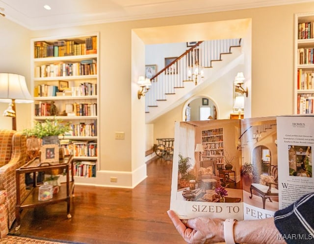 living area with built in features, stairway, ornamental molding, wood finished floors, and baseboards