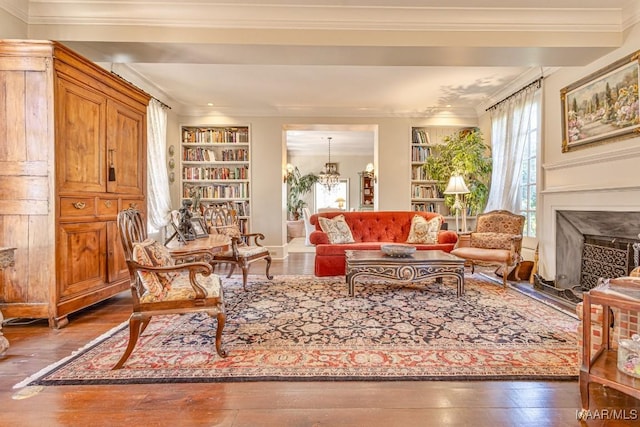 sitting room featuring an inviting chandelier, built in shelves, and crown molding