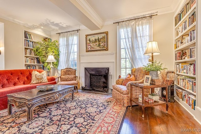 living area featuring wood-type flooring, built in features, a fireplace with raised hearth, and crown molding