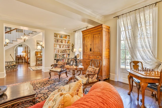 sitting room featuring baseboards, arched walkways, wood finished floors, and ornamental molding