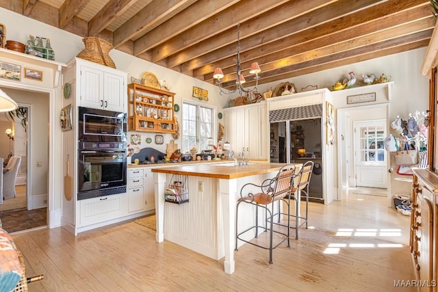 kitchen with white cabinets, light wood-style flooring, wood counters, a kitchen island, and built in fridge