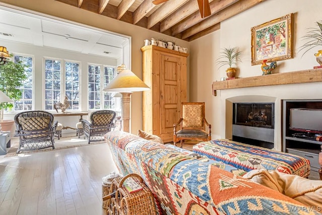 living area with beam ceiling, a fireplace, and hardwood / wood-style floors