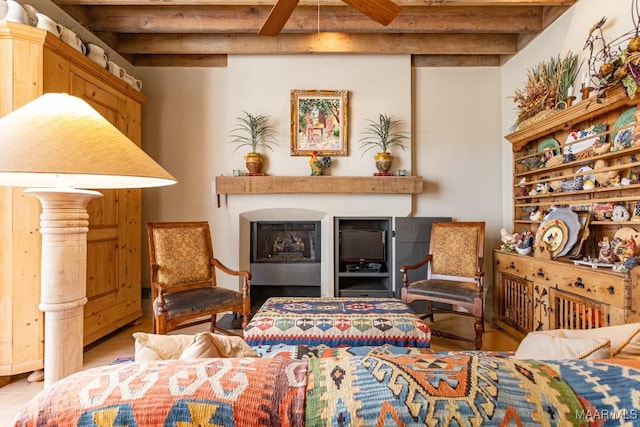 living area with a fireplace, beamed ceiling, and wood finished floors