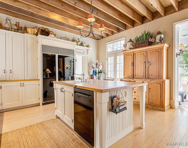 kitchen with black dishwasher, butcher block countertops, light wood-type flooring, a sink, and built in fridge