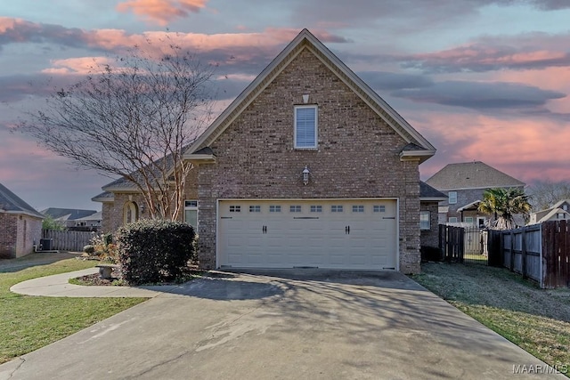 traditional-style house featuring a garage, concrete driveway, brick siding, and fence