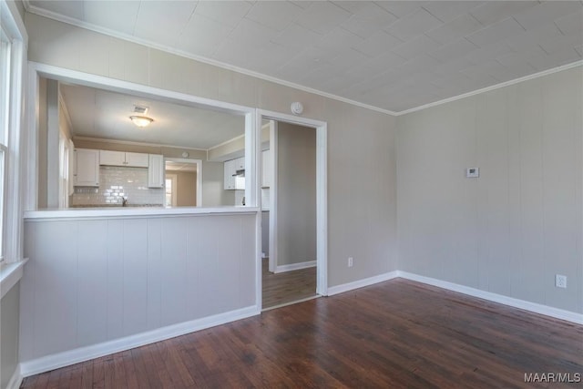 unfurnished living room with dark wood-style floors, baseboards, and crown molding