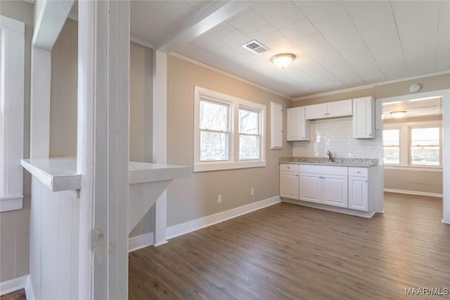 kitchen featuring a sink, wood finished floors, white cabinetry, and crown molding