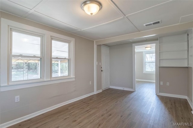 spare room with wood finished floors, visible vents, and baseboards