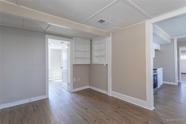 spare room with visible vents, baseboards, and wood finished floors