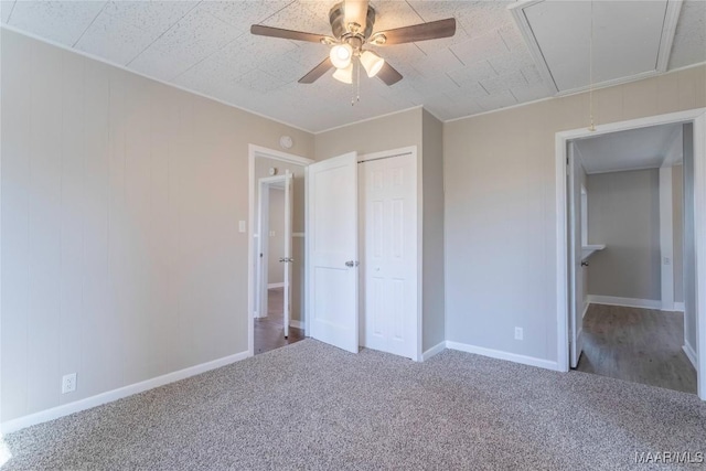 unfurnished bedroom with carpet floors, a closet, attic access, ceiling fan, and baseboards