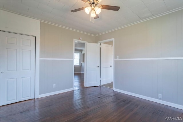 unfurnished bedroom with a ceiling fan, baseboards, ornamental molding, a closet, and dark wood-style floors