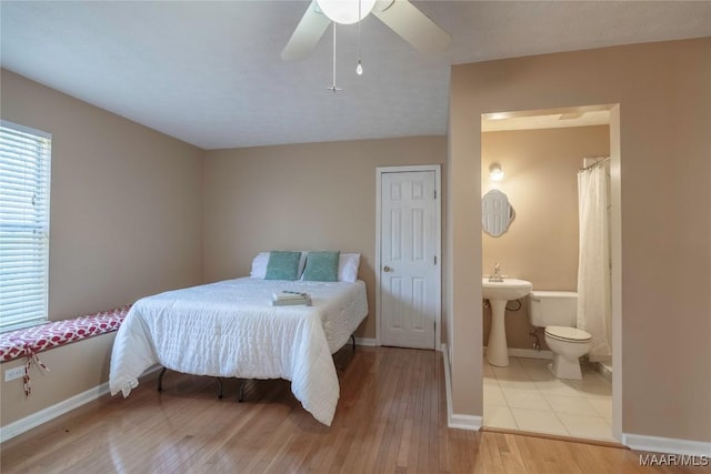 bedroom featuring a sink, connected bathroom, baseboards, and wood finished floors