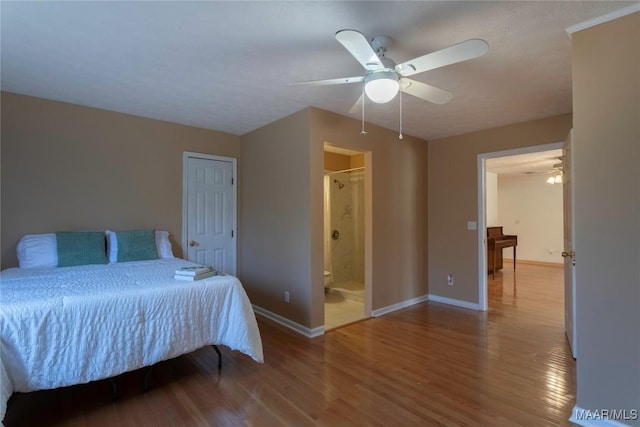 bedroom featuring ceiling fan, connected bathroom, baseboards, and wood finished floors