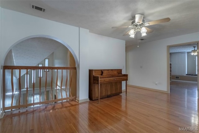 spare room with visible vents, baseboards, a ceiling fan, wood-type flooring, and a textured ceiling