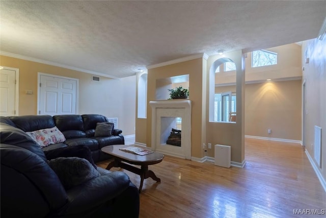 living room with baseboards, visible vents, a textured ceiling, light wood-type flooring, and a fireplace