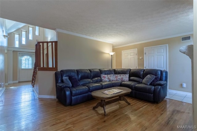 living area featuring crown molding, visible vents, a textured ceiling, wood finished floors, and baseboards