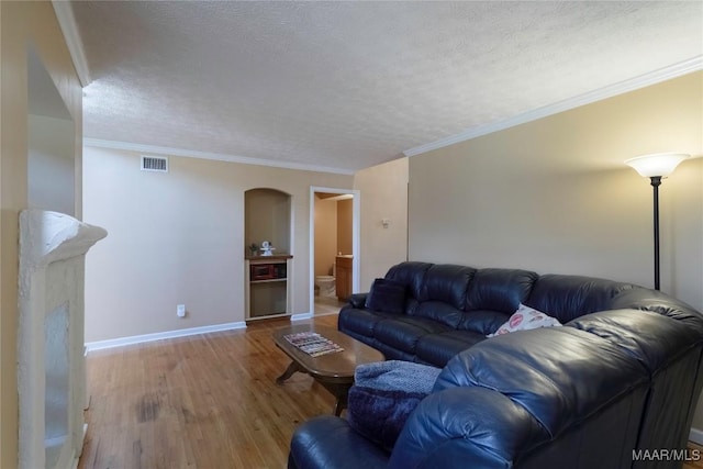 living room with baseboards, a textured ceiling, visible vents, and wood finished floors