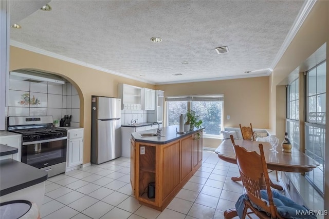 kitchen with visible vents, a kitchen island with sink, stainless steel appliances, crown molding, and a sink