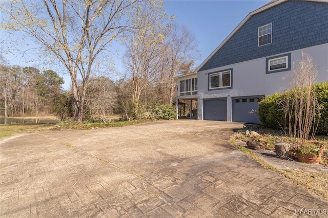 view of side of home with driveway, an attached garage, and stucco siding