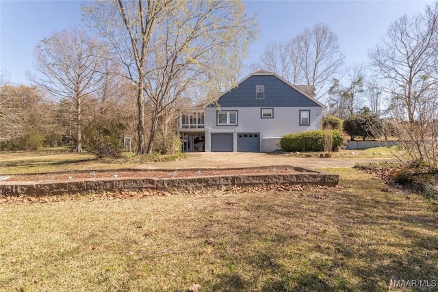 back of property featuring an attached garage, dirt driveway, and a yard