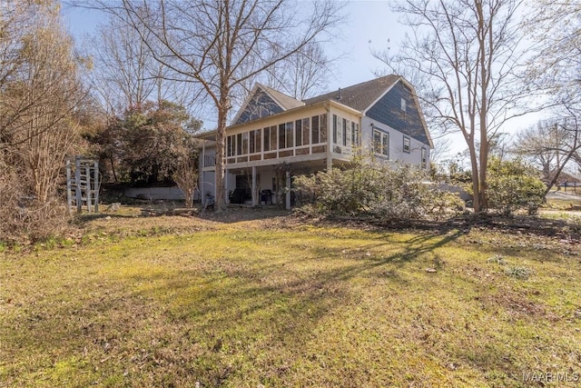 rear view of property featuring a sunroom and a lawn