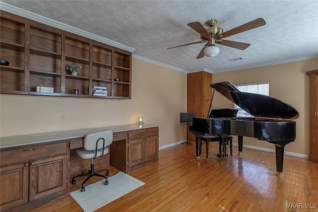 office space with a textured ceiling, ornamental molding, built in study area, and light wood-style flooring